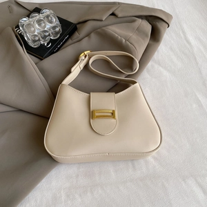 Detail of elegant cream shoulder bag with textured gold buckle and adjustable strap