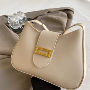 Detail of the golden rectangular buckle on a beige cream leather shoulder bag