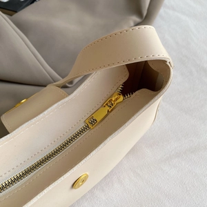 Detail of beige lychee pattern bag with gold zipper and secure magnetic closure