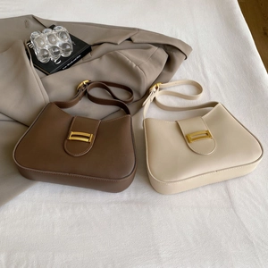 Detail view of dark brown and beige matte leather shoulder bags with gold metal buckle