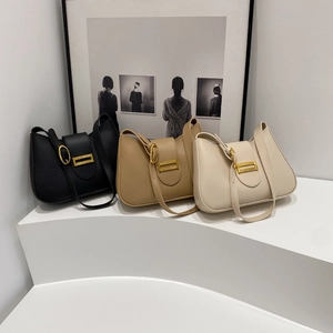 Close-up of three shoulder bags in black, khaki, and cream with golden metal buckles
