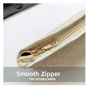 Macro shot of minimalist woven leather clutch featuring a smooth gold metallic zipper closure