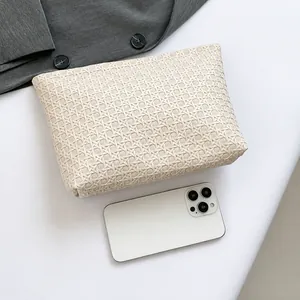 Detail view of woven envelope clutch next to a smartphone showing real-life size and texture
