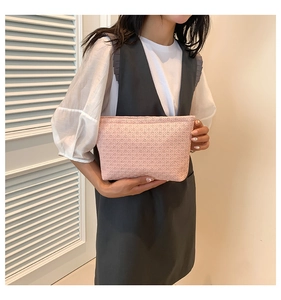 Detail of light pink woven clutch bag with textured mesh pattern and minimalist design