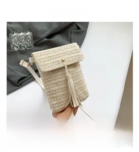 Detail view of woven straw bag featuring a golden magnetic buckle and tassel fringe