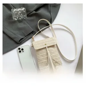 Macro view of woven straw crossbody phone bag with tassel detail and magnetic flap closure