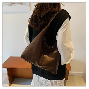 Détail d'un grand sac Hobo marron foncé montrant la texture cuir vintage et la bandoulière