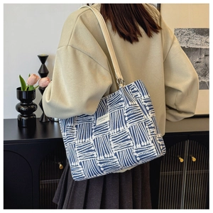 Detail of blue and white geometric woven tote bag with a white leather fashion label