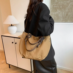 Brown canvas tote bag with leather straps and metal rivets for casual office commuting