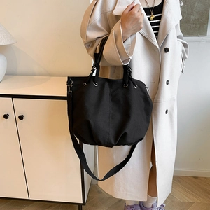 Black canvas tote bag with drawstring detail and adjustable wide shoulder strap for women