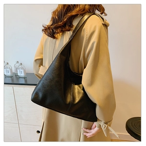 Détail du grand sac cabas hobo noir en cuir mat plissé porté à l'épaule par le mannequin
