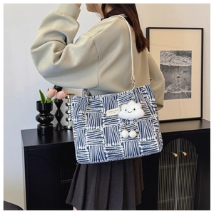 Detail of blue and white geometric tote bag with cloud charm on female shoulder