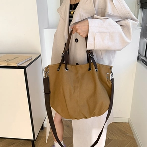 Retro large brown canvas tote bag with thick strap held by a model in beige coat
