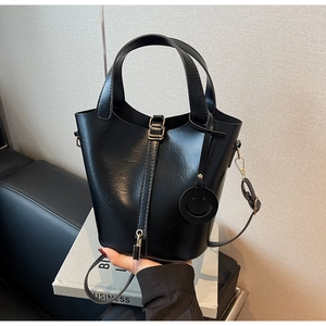 Détail du sac seau noir brillant avec fermoir métallique et breloque décorative smiley