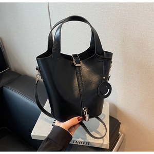 Détail du sac seau noir en simili cuir avec sangle verticale et pendentif cadenas en métal