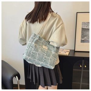 Detail of green geometric knit tote bag showing woven texture and beige leather strap