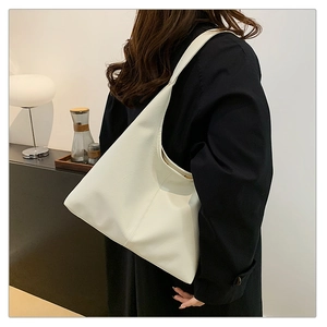 Macro shot of white leather tote bag with subtle grain texture and broad shoulder strap
