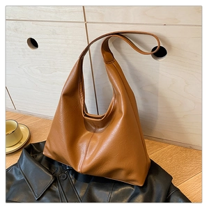 Détail d'un sac Hobo marron avec texture litchi sur une veste en cuir noir