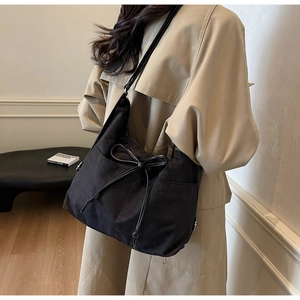 Detail der schwarzen Wildleder-Hobo-Tasche mit Schleife und Seitentasche am Model