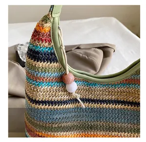 Detail of colorful striped woven shoulder bag with faux leather handle and bead charm