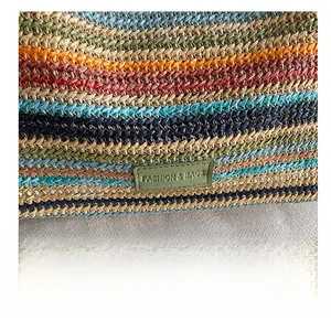 Detailed close-up of multi-colored woven straw tote bag with green leather logo patch