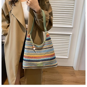 Detail of colorful woven tote bag featuring multi-color stripes and green leather strap