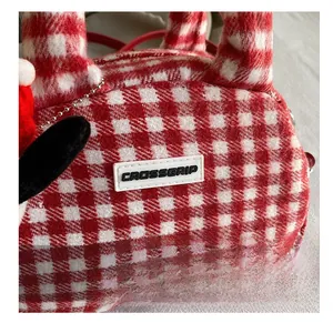Close-up of red and white plaid plush bag showing soft texture and logo detail