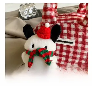 Detail of white plush charm with red knit hat and striped scarf on a plaid bowling bag