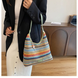 Detail of colorful woven tote bag with rainbow stripes and light green leather straps