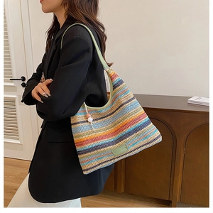 Detail view of colorful striped woven tote bag with green leather handles and bead charm