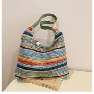 Détail du sac cabas en paille à rayures avec bandoulière verte et breloque perlée