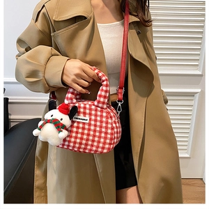 Detail der rot-weiß karierten Plüschhandtasche mit Schneemann-Anhänger am Trenchcoat