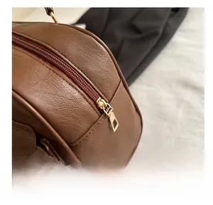 Close-up of premium golden metal zipper on brown pebble leather pillow bag