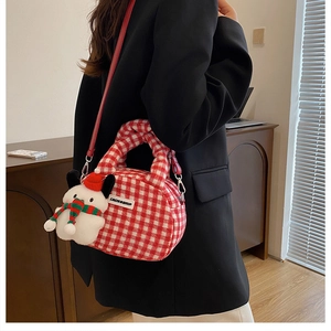 Detail der rot-weiß karierten Handtasche mit Schneemann-Anhänger und rotem Leder Schultergurt