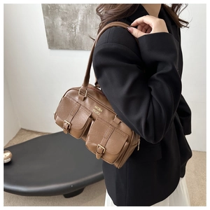 Brown retro shoulder bag with twin front pockets and gold logo shown on a model