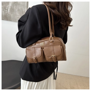 Detail view of brown faux leather shoulder bag with buckle pockets and gold-toned text