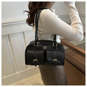 Close-up of black retro pillow bag featuring dual front pockets and gold metal hardware