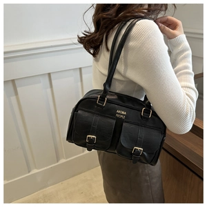 Detail of vintage black faux leather shoulder bag with gold buckles and dual front pockets