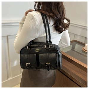 Close-up of black PU leather tote bag with dual front flap pockets and gold hardware buckles