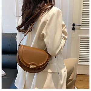 Borsa a sella marrone vintage con chiusura dorata indossata per mostrare dimensione