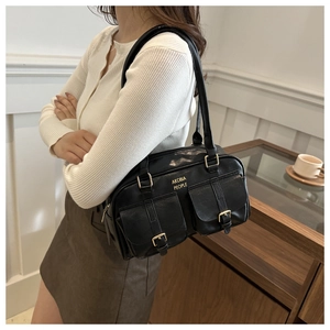 Detail of black leather shoulder bag with double flap pockets and gold buckles on a model
