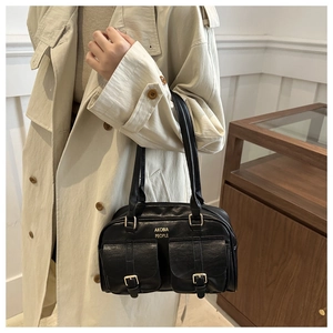 Close-up of black retro leather shoulder bag with gold buckles and dual front pockets