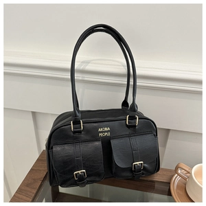 Close-up of black textured leather bag featuring gold buckles and two front pockets