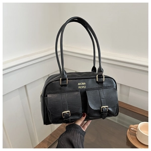 Close-up of black leather bag with dual front pockets and gold metal buckle hardware
