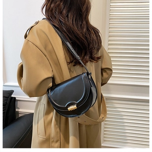 Dettaglio di una borsa a sella vintage nera con una distintiva chiusura a cilindro dorata