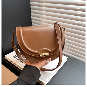 Dettaglio di una borsa a sella in pelle marrone con elegante chiusura a spirale dorata