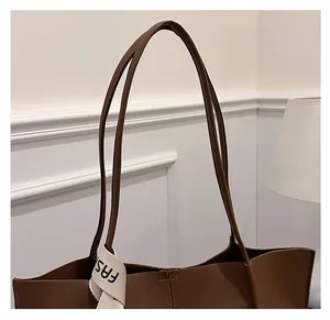 Detail eines braunen Leder-Shoppers mit einem schwarz-weißen Webband mit Buchstaben