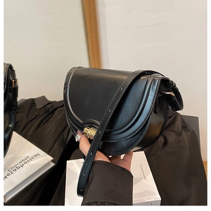 Dettaglio della borsa a sella in pelle nera con fibbia in metallo dorato testurizzato