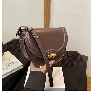 Dettaglio borsa a sella in pelle marrone vintage con fibbia a spirale dorata
