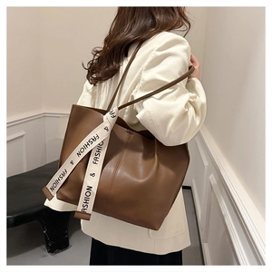 Detailaufnahme der braunen Leder-Tote-Bag mit dekorativem Fashion-Schriftzug am Griff